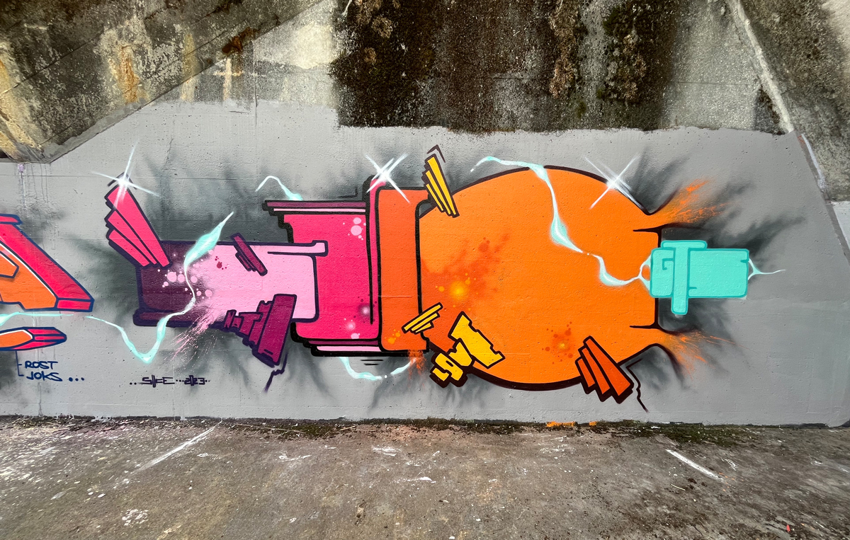 Schriftzug pink-orange auf einer grauen Industriewand