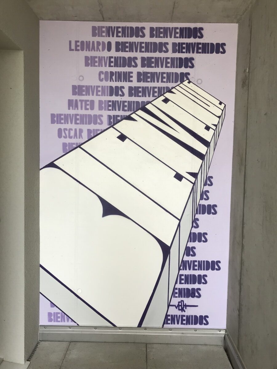 Schriftzug Bienvenue auf Wand aus Sichtbeton neben Hauseingang