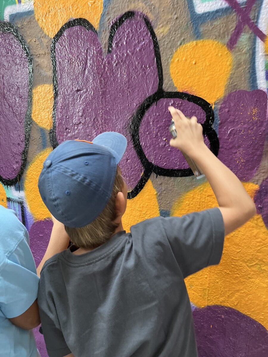 Kind sprayt in einem Workshop an eine Betonwand