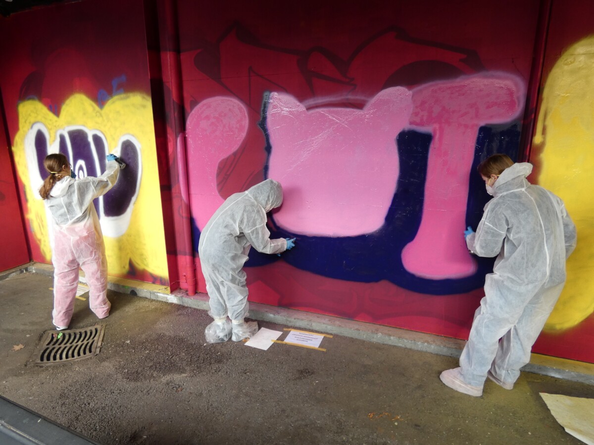 Jugendliche sprayen ein Graffiti an eine Wand