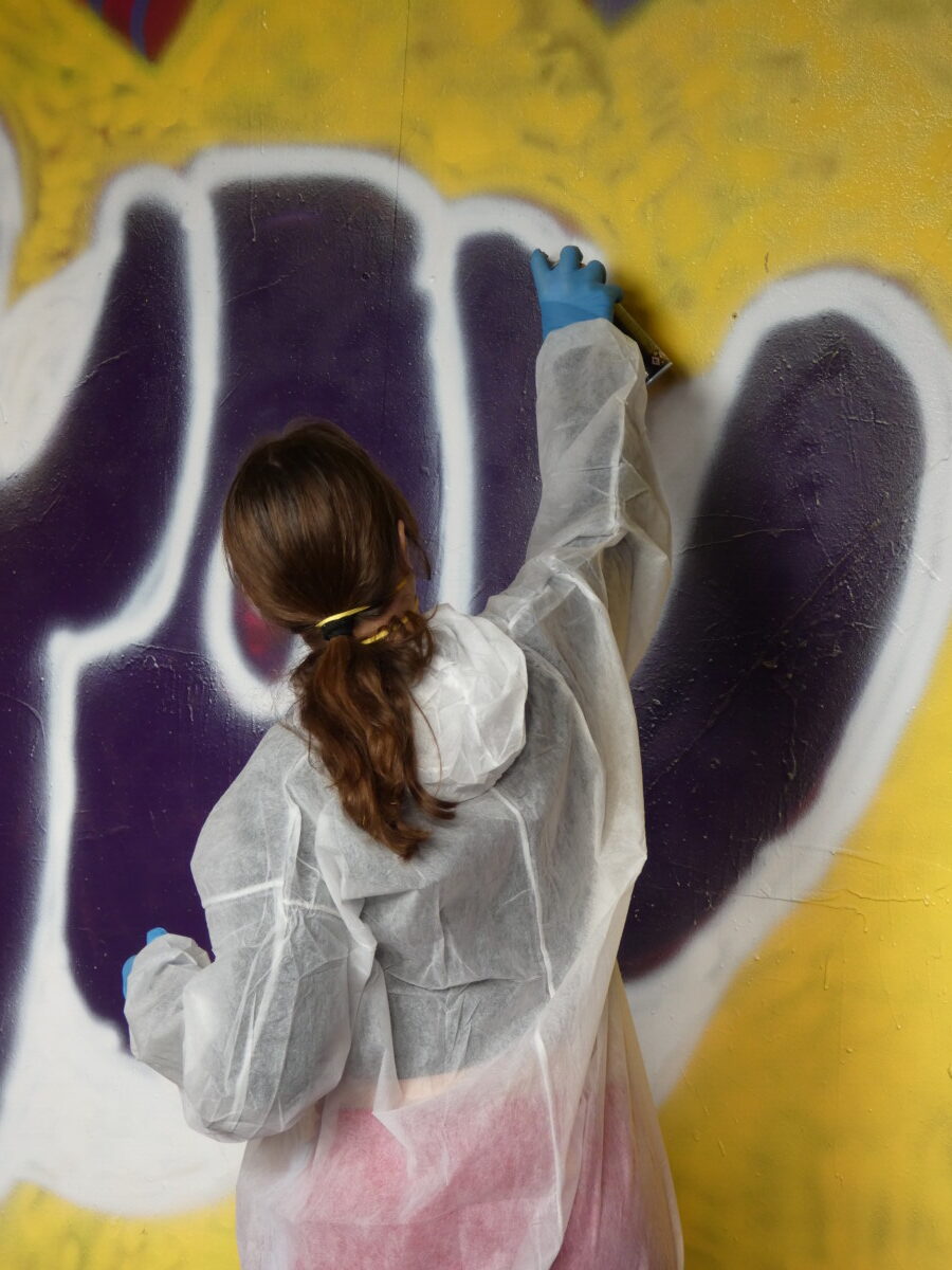 Jugendliche sprayt einen gelben Schriftzug You